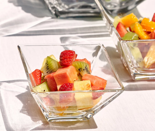 Glass bowls filled with a colorful fruit salad on a white surface