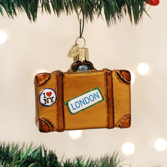 Decorative suitcase ornament with 'I Love NY' and 'London' stickers on a Christmas tree.