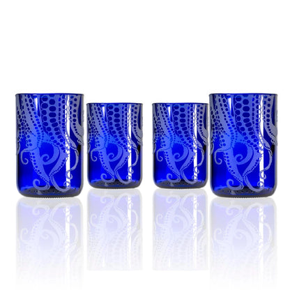 Set of four blue glass tumblers with white patterns on a white background
