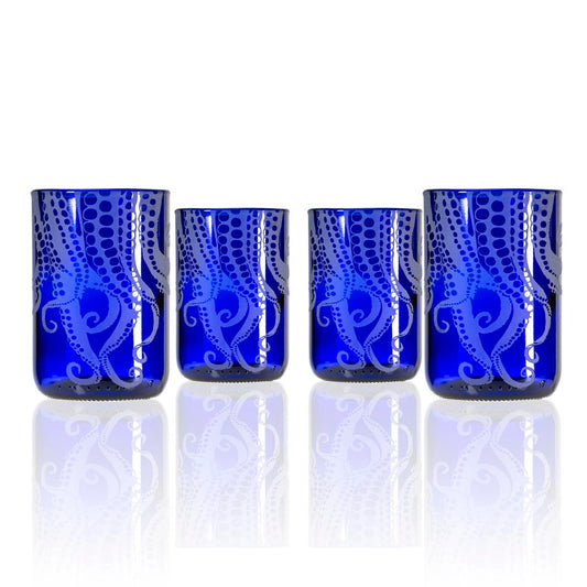 Set of four blue glass tumblers with white patterns on a white background