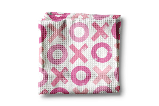 Folded baby blanket with pink 'XO' pattern on a white background