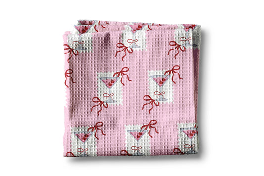 Pink textured blanket with bow and heart pattern on a white background