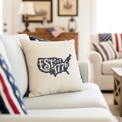 Decorative pillow with 'EST. 1776' design on a couch in a living room setting.