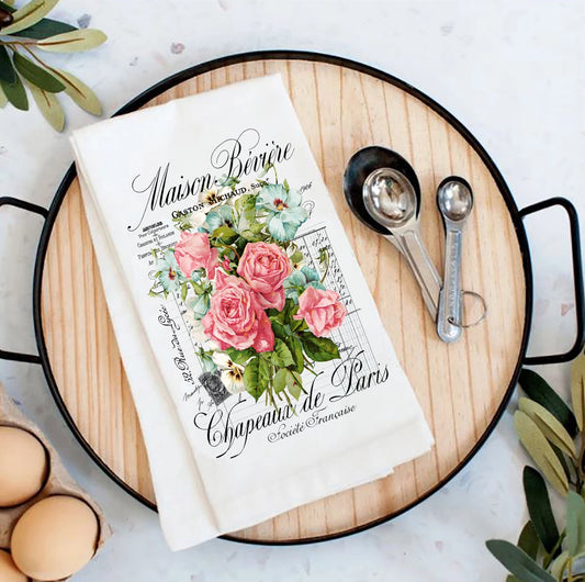 Floral-themed kitchen towel on a wooden board with measuring spoons and eggs.