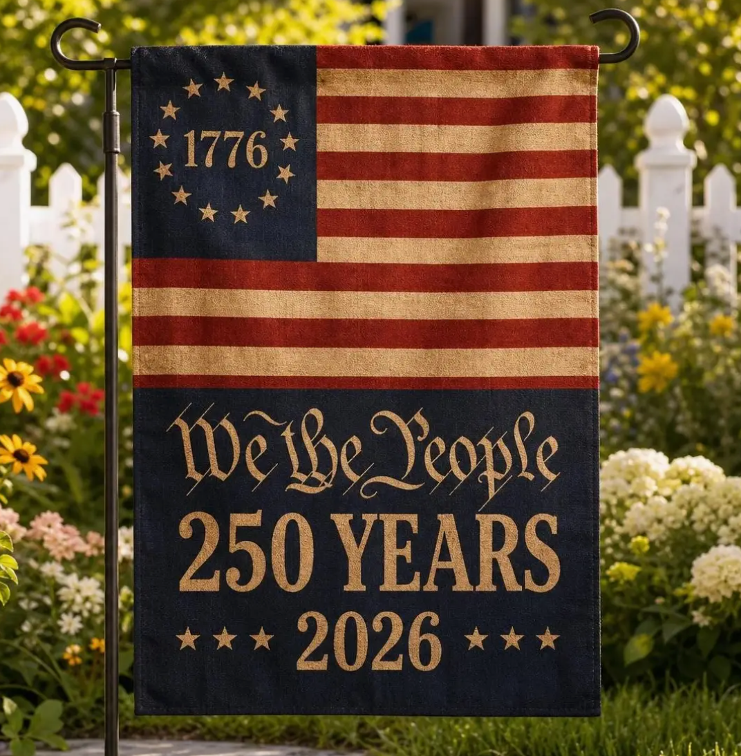 Decorative flag with 'We the People 250 Years 1776-2026' text in a garden setting.