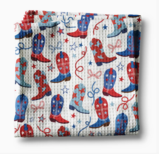Folded kitchen towel with red, white, and blue cowboy boot pattern on a white background
