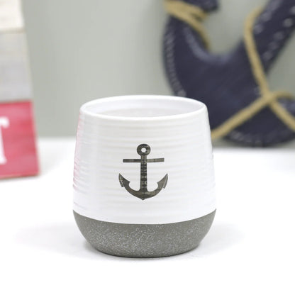 White ceramic cup with gray anchor design on a white background