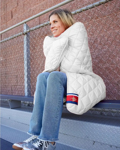 Person sitting on a step with a large white pillow, wearing a white quilted jacket.