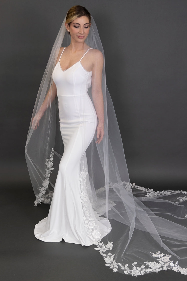 Bride in a white wedding dress with a long veil against a dark background