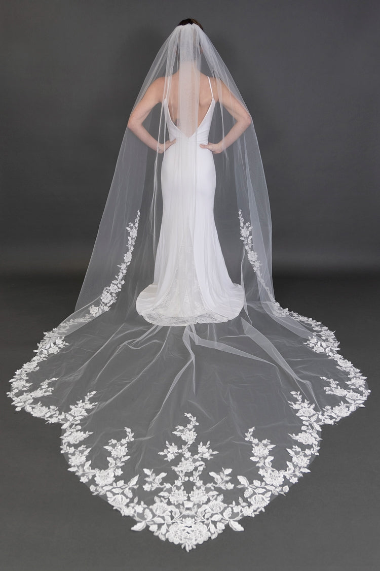 White wedding dress with a long embroidered veil on a dark background