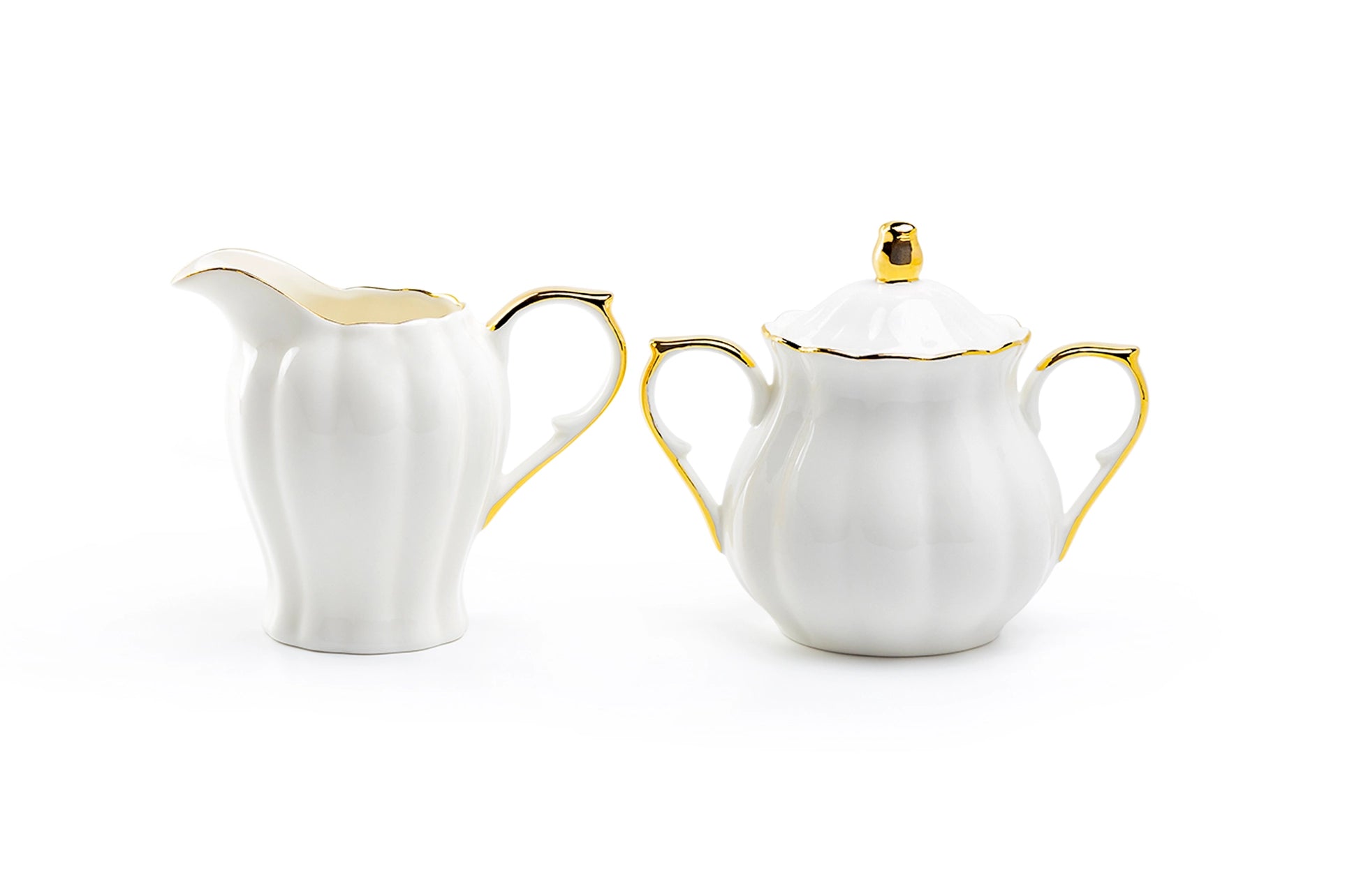 White ceramic creamer and sugar bowl set with gold accents on a white background
