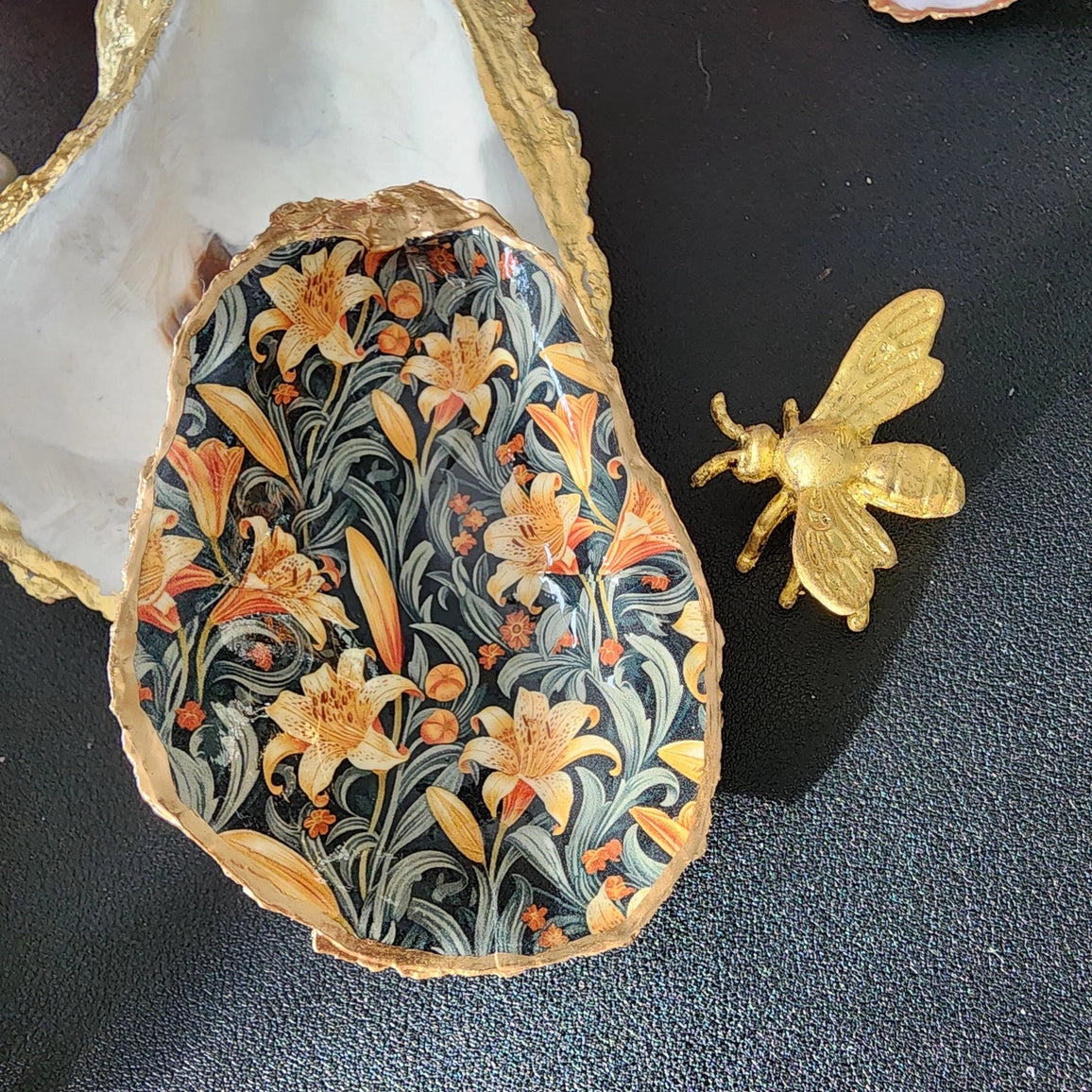 Decorative stone with floral pattern and gold bee on a dark surface
