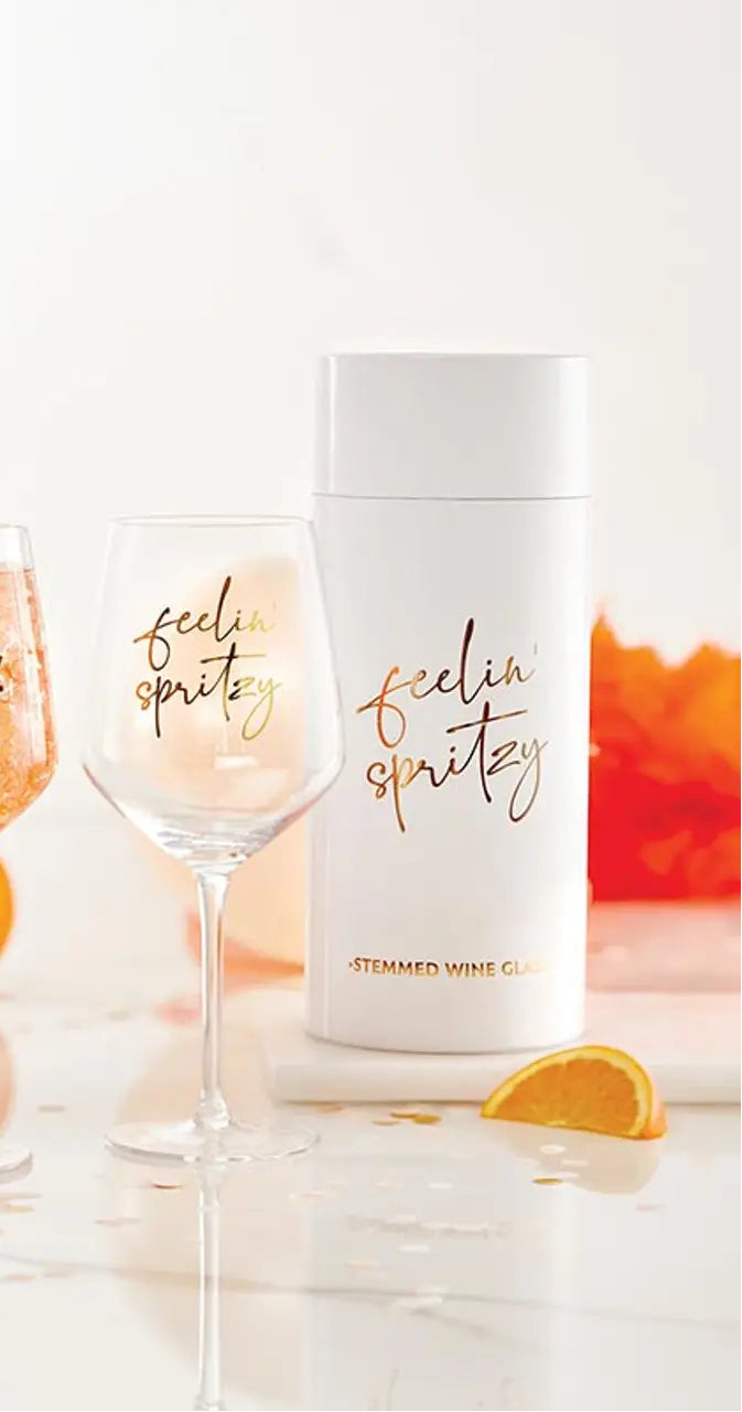 Wine glasses and bottles with 'The Spritz Club' branding on a reflective surface.