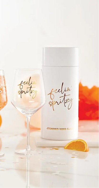 Wine glasses and bottles with 'The Spritz Club' branding on a reflective surface.