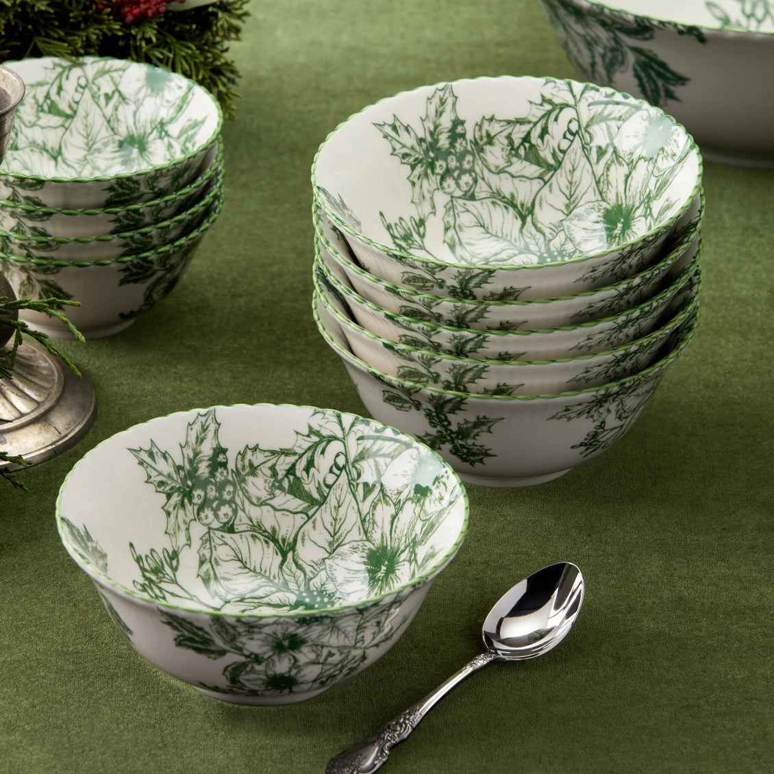 Set of white bowls with green floral patterns on a green surface with a spoon.
