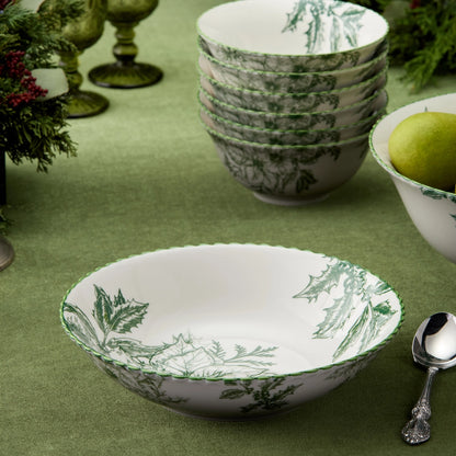 Set of white bowls with green leaf patterns on a green tablecloth.