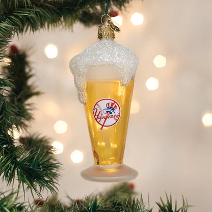 Christmas ornament shaped like a glass of beer with a Yankees logo, hanging on a tree.