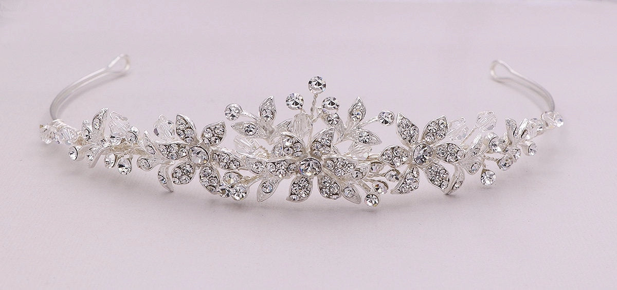 Silver tiara with floral and leaf designs on a light gray background