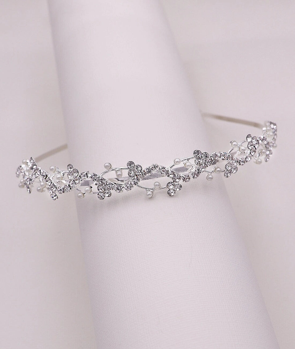 Silver tiara with floral and bead details on a white background
