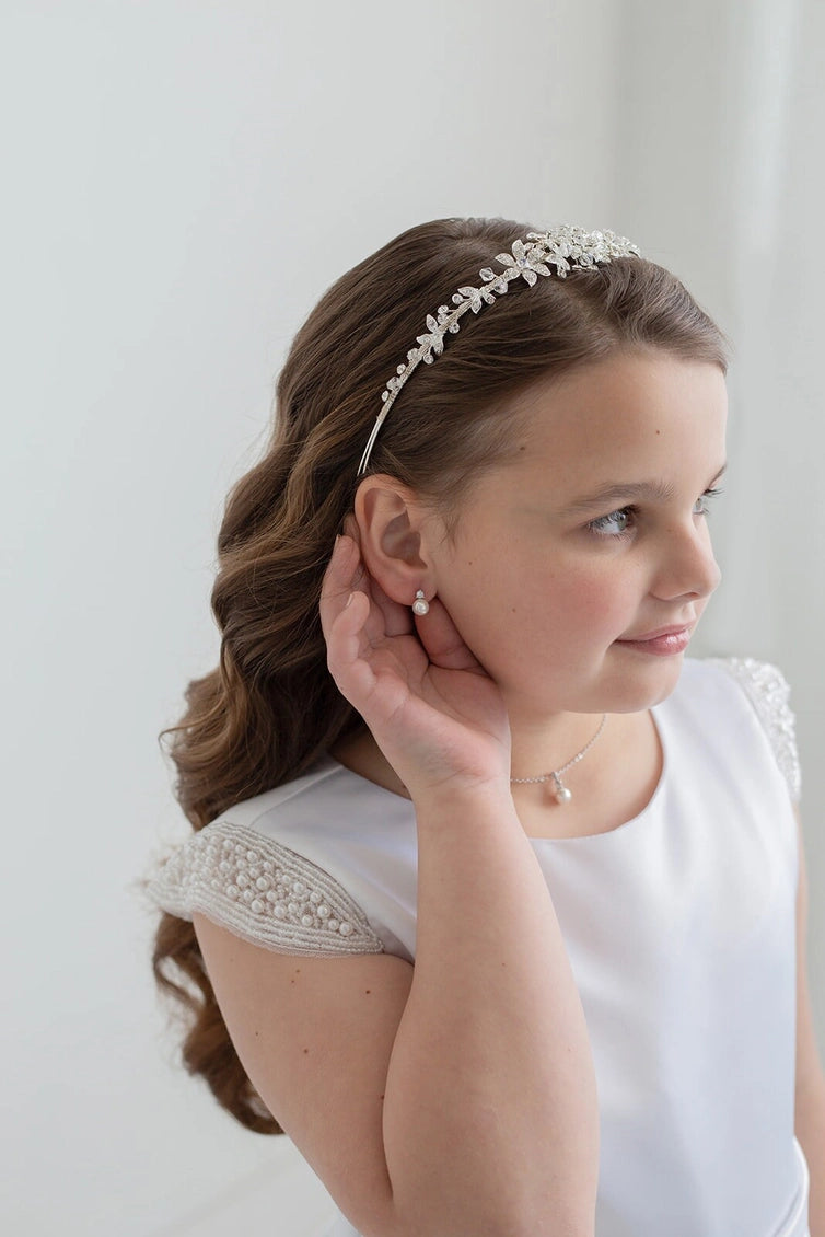 Young girl wearing a headband and earrings against a white background
