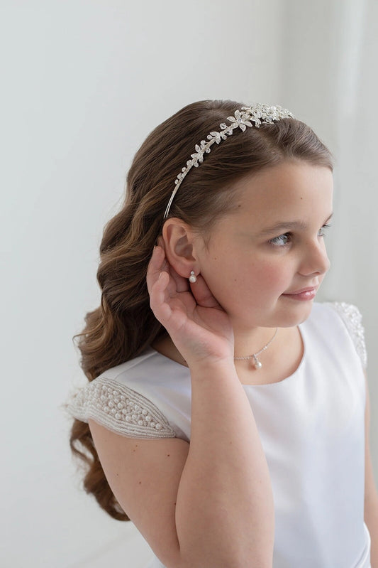 Young girl wearing a headband and earrings against a white background