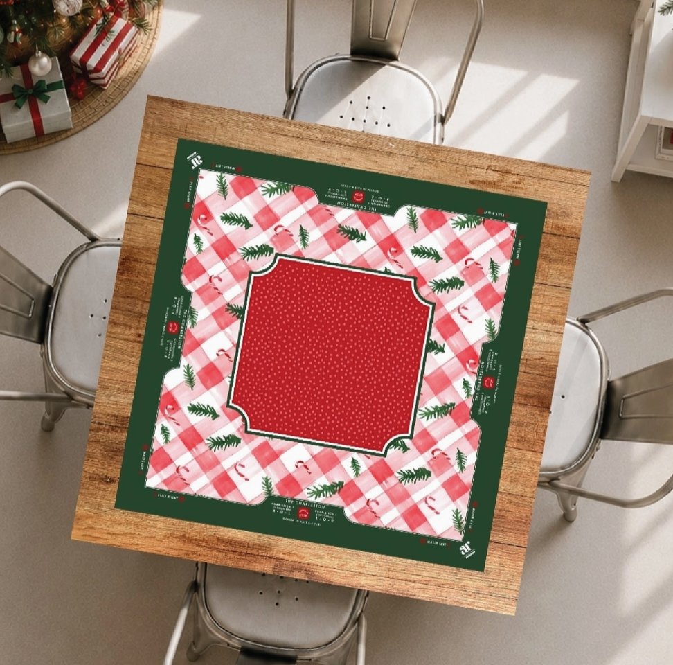 Candy Cane Lane Christmas Mahjong mat displayed on a holiday game table with pink gingham, red center and evergreen border.