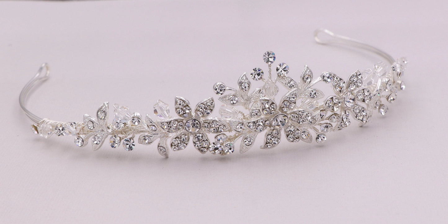 Silver tiara with floral and leaf designs on a white background