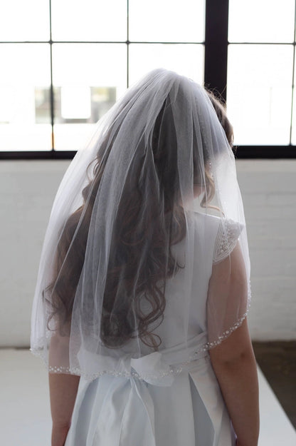 young girl wearing white dress and communion veil