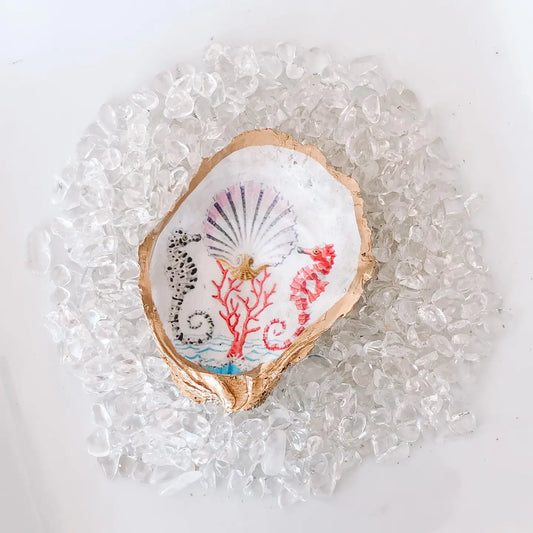 Decorative shell with seahorse and coral design on a white background