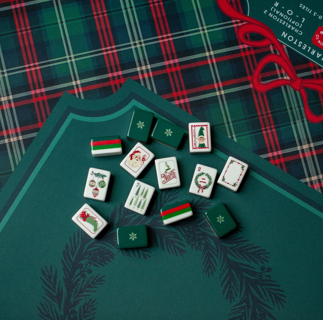 Christmas Mahjong tiles displayed on Evergreen & Tartan Mahjong mat featuring deep green, red tartan plaid and ribbon details.