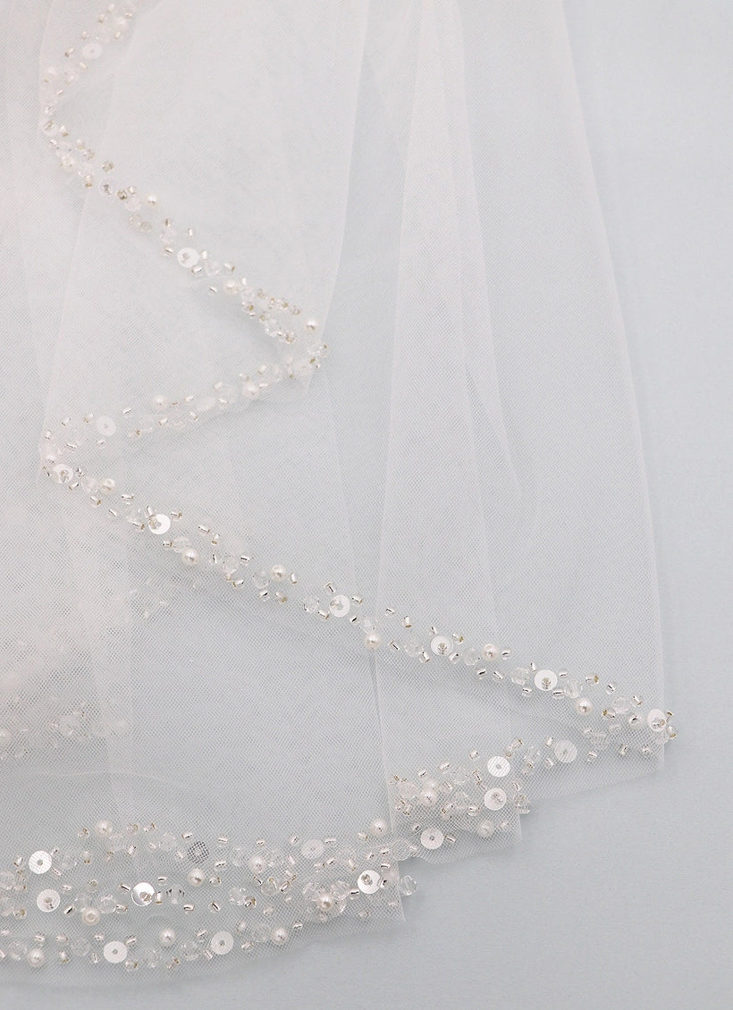 Close-up of a sheer fabric with sequin embellishments on a light gray background