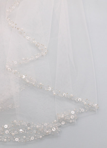 Close-up of a sheer fabric with sequin embellishments on a light gray background