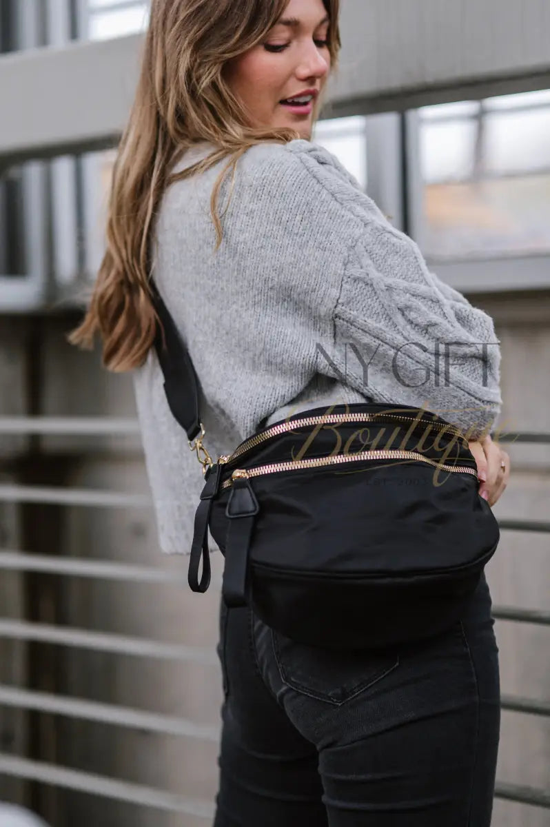 Woman wearing a black waist bag with gold zippers in an urban setting