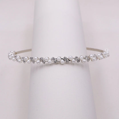 Pearl and crystal headband on a jewelry rack against a white background