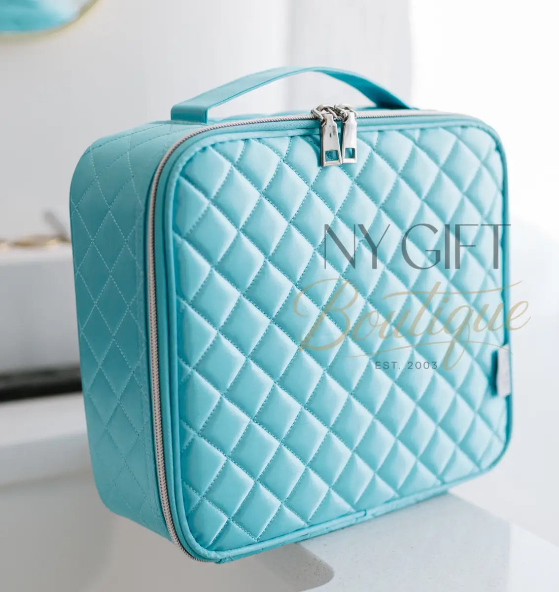 Turquoise quilted makeup bag on a white surface with a blurred background