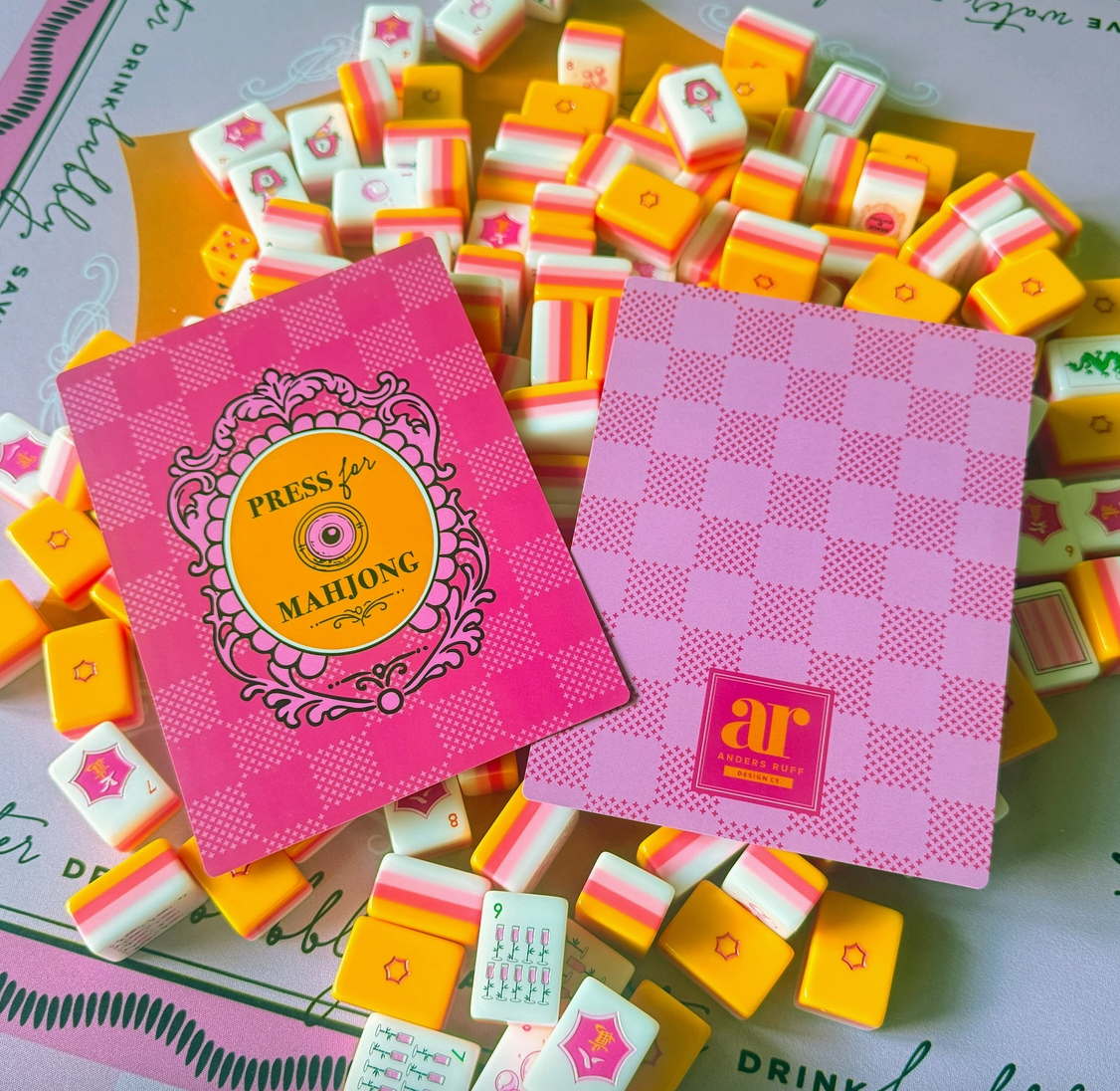 Sip & Shuffle Mahjong tile shufflers displayed with colorful Mahjong tiles on a coordinating game mat.